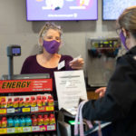 Catering Services Director Molly Boyne serves a customer from behind a clear protective barrier in Summit Marketplace in the Anderson Student Center. Mark Brown/University of St. Thomas