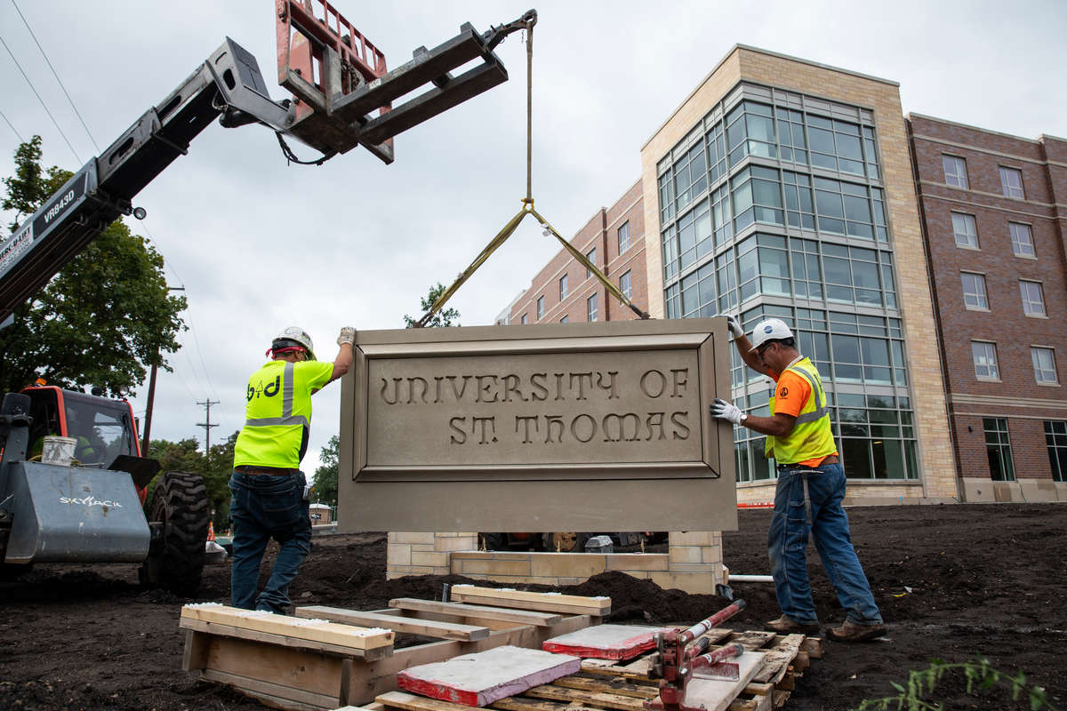 A crew for B&D Masonry installs a new University of St. Thomas monument sign at the corner of Cleveland and Selby in front of the newly completed Tommie North Residence Hall in St. Paul on August 28, 2020.