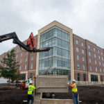 A crew for B&D Masonry installs the new sign in front of Tommie North Residence Hall.