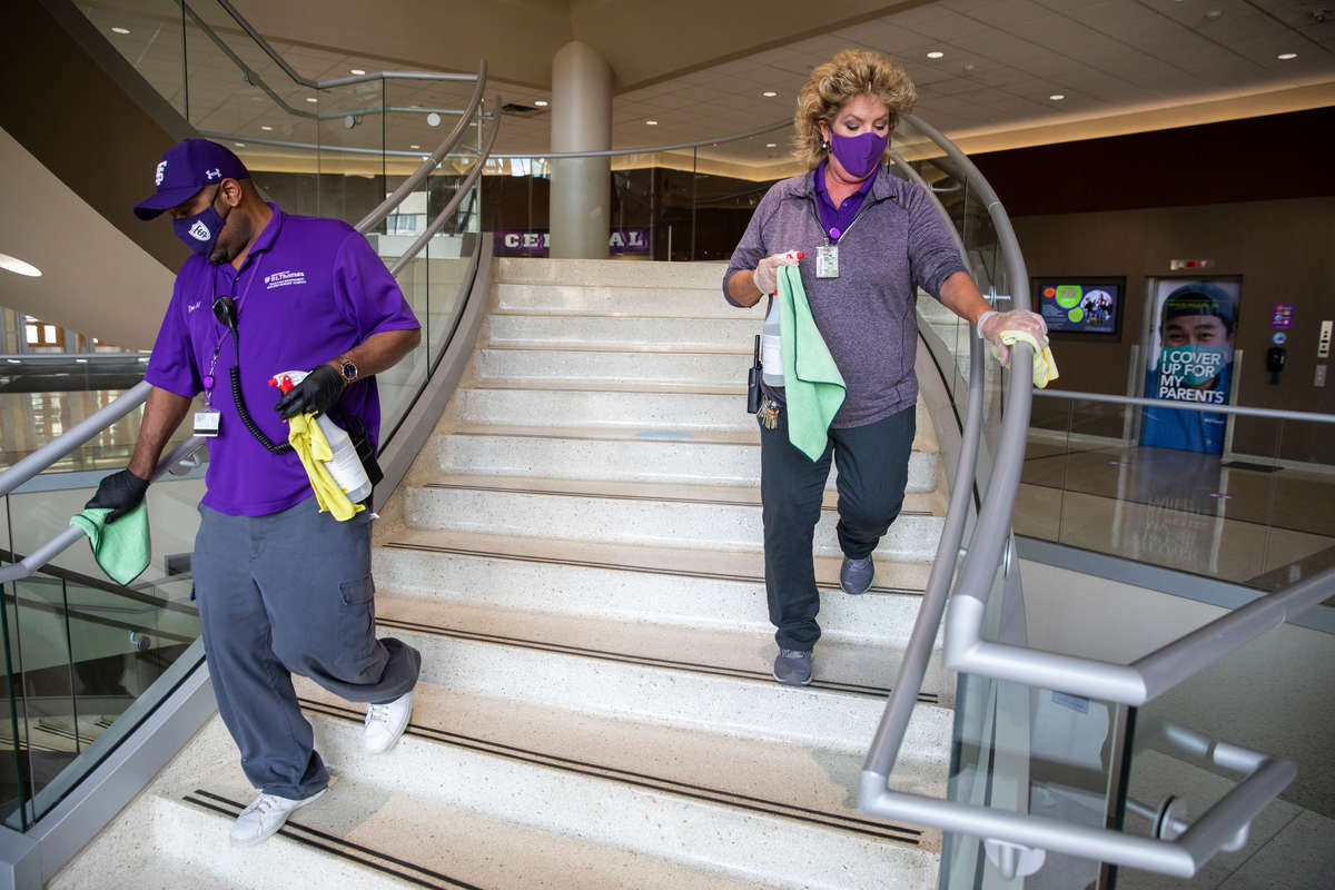 Facilities Management staff Candy Sauer, right, and Dennis Hollie work together to sanitize surfaces in the Anderson Student Center. Liam James Doyle/University of St. Thomas