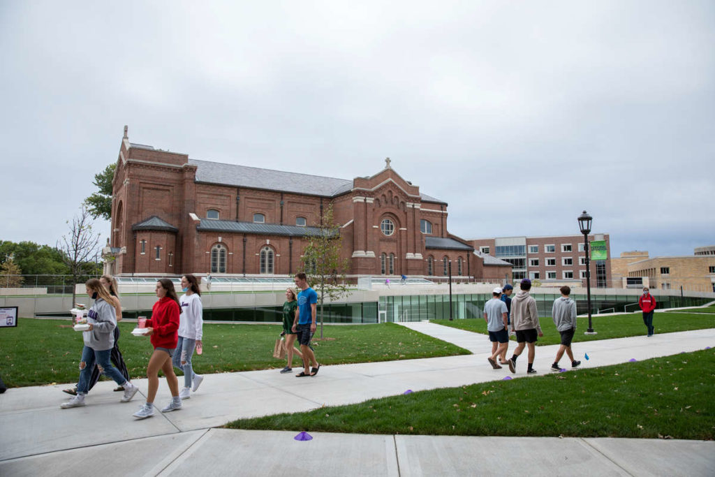 Students walk through the upper quad and past the Iversen Center for Faith and Aquinas Chapel.