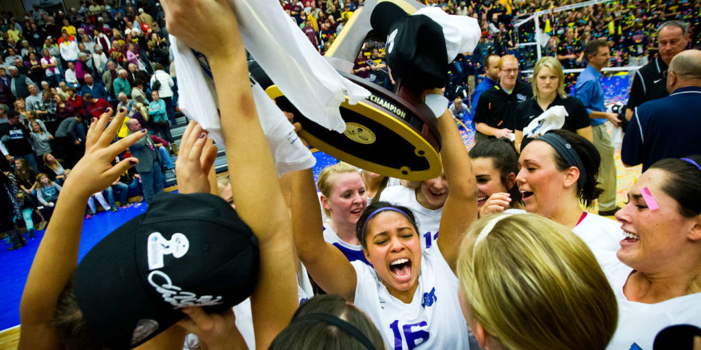 Kia Johnson hoists the national championship trophy as her teammates celebrate after UST's NCAA Division III Volleyball title game against Calvin College in Holland, Michigan on November 17, 2012. The game took place at Hope College in the DeVos Fieldhouse before a record crowd. UST won the title after coming back from two sets down to defeat number one ranked Calvin 3-2.