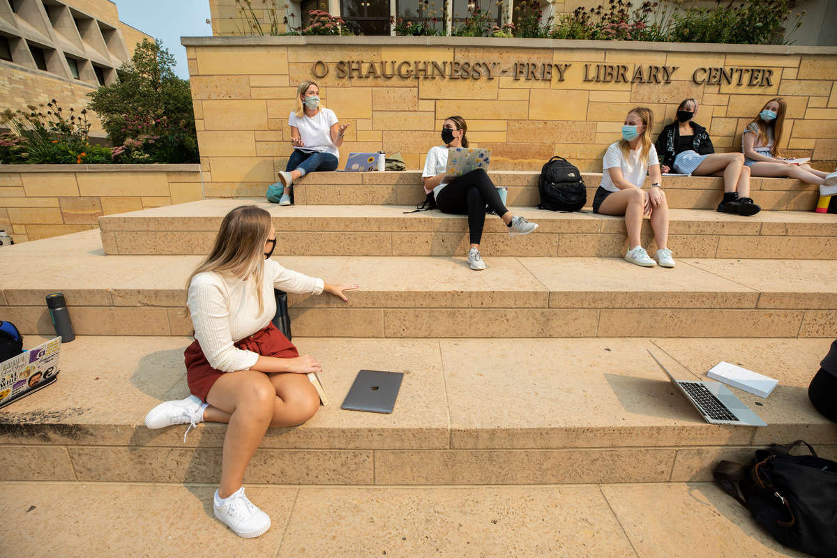 Students sit on the steps of the O'Shaughness-Frey Library during a communications class. Liam James Doyle/University of St. Thomas
