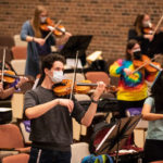 Student musicians practice during Professor Matthew George’s Orchestra class while maintaining a social distance in the Brady Education Center Auditorium. Liam James Doyle/University of St. Thomas