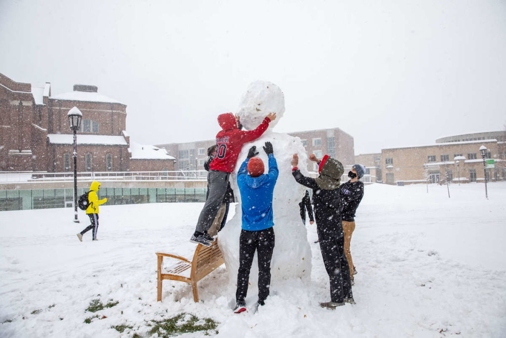 Students make a large snowman on the upper quad during a fall snowstorm in October. Mark Brown/University of St. Thomas