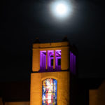 The O'Shaughnessy-Frey Library Center under a bright moon on the lower quad.