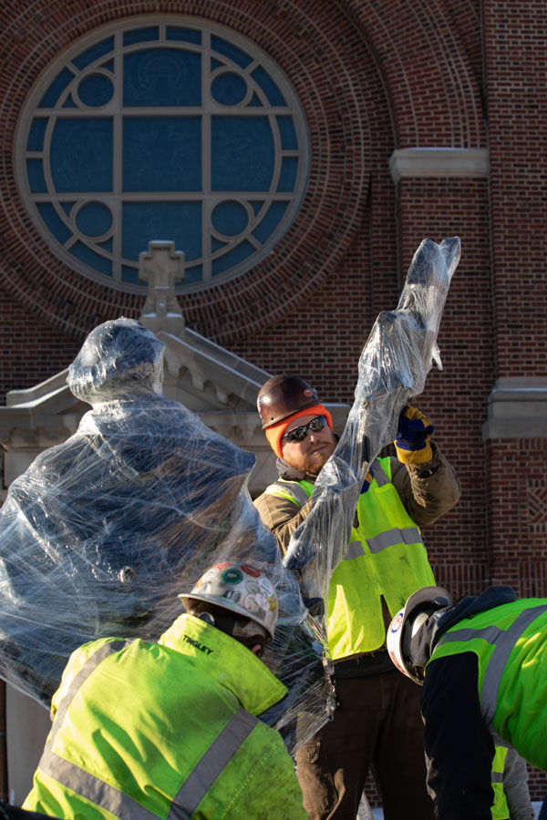 Workers unwrap the new sculpture of St. Thomas Aquinas by Canadian artist Timothy P. Schmalz. Mark Brown/University of St. Thomas