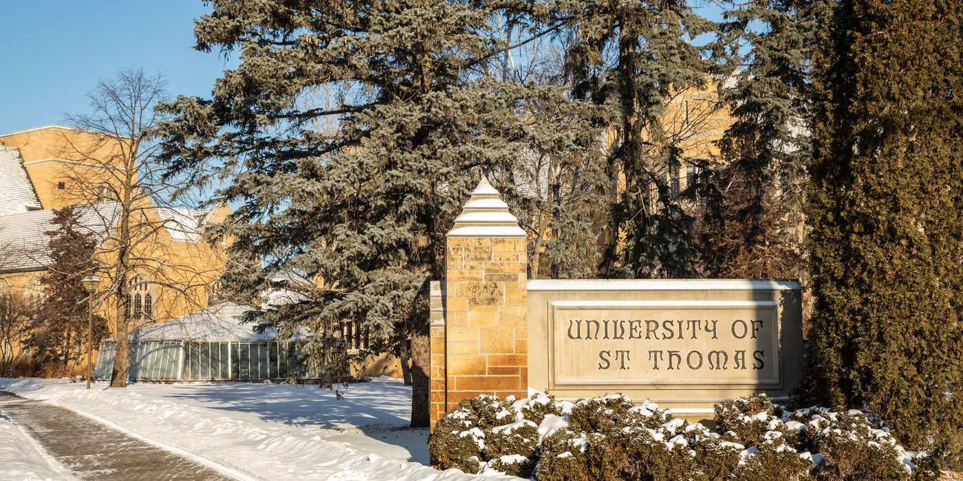 The St. Thomas monument sign on the corner of Cleveland and Summit on a cold sunny winter day on the St. Paul campus.