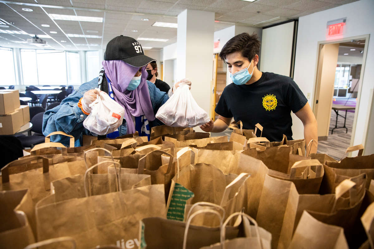 Students Naima Jama, left, and Alonso Ruiz, right, work to organize and fill bags with food items.