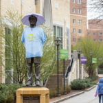 The statue of John Ireland is dressed in a t-shirt and an umbrella hat during the Spring into Spring event hosted by Student Affairs.