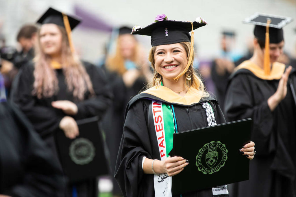 A student smiles at the commencement ceremony for graduate programs. Mark Brown/University of St. Thomas