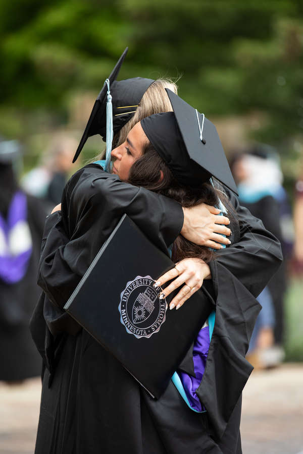Students embrace after the commencement ceremony for graduate programs. Mark Brown/University of St. Thomas