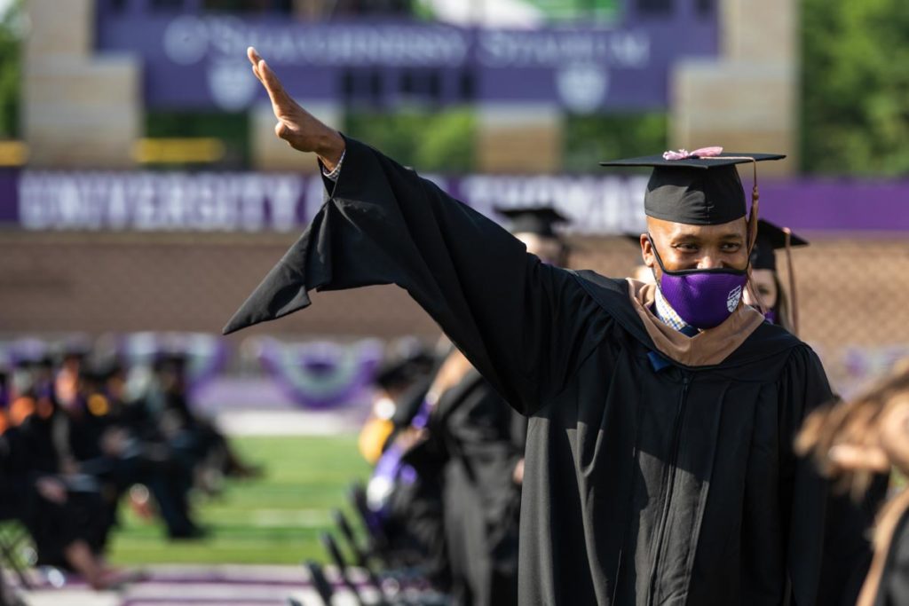 A student waves to the crowd during the commencement ceremony for graduate programs in the Opus College of Business and School of Engineering. Mark Brown/University of St. Thomas