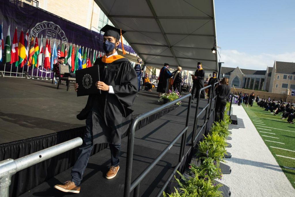 A student walks across stage during the commencement ceremony for graduate programs in the Opus College of Business and School of Engineering. Mark Brown/University of St. Thomas