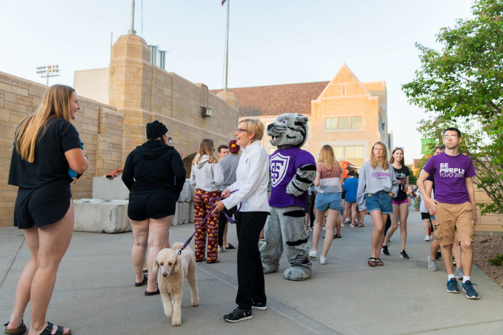 Tommie the mascot, University president Julie Sullivan and her dog Bella socialize with students. Liam James Doyle/University of St. Thomas