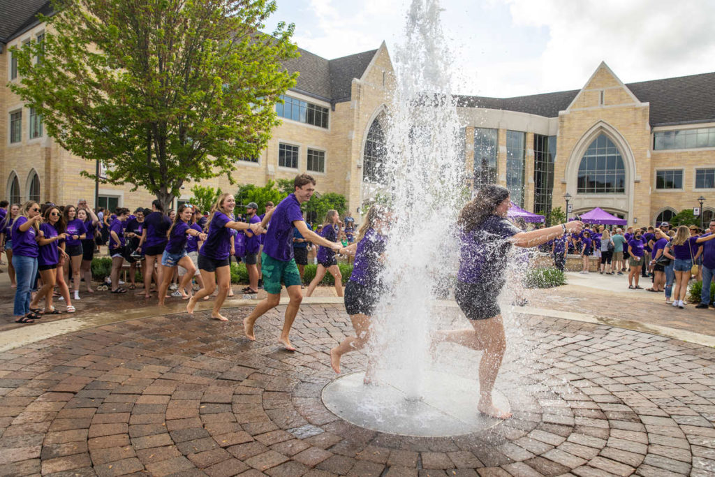 Students celebrate by running through the water fountain on Monahan Plaza. Mark Brown/University of St. Thomas