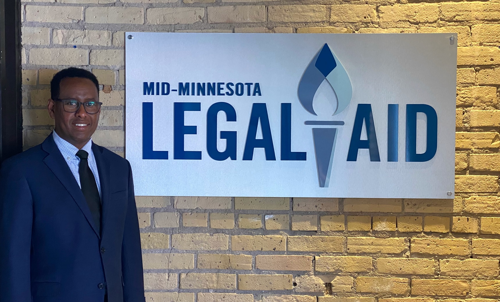 Abdiasis Hirsi with Mid-Minnesota Legal Aid logo.