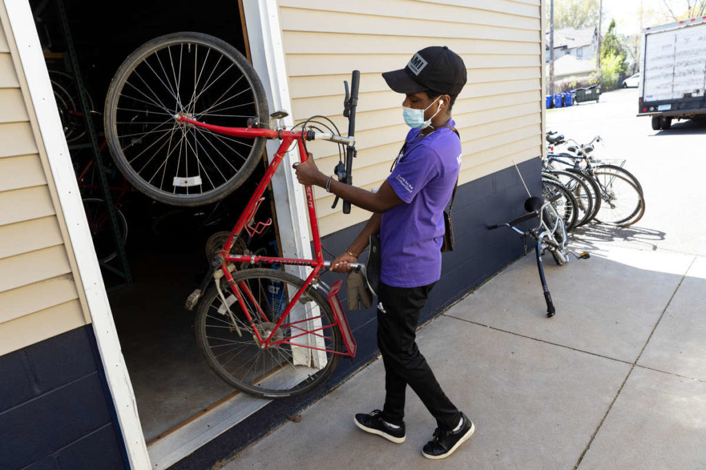 A student volunteer carries a donated bike into a storage area at Express Bike Shop during The Big Event volunteer day facilitated by the Center for the Common Good on May 1, 2021, in St. Paul.