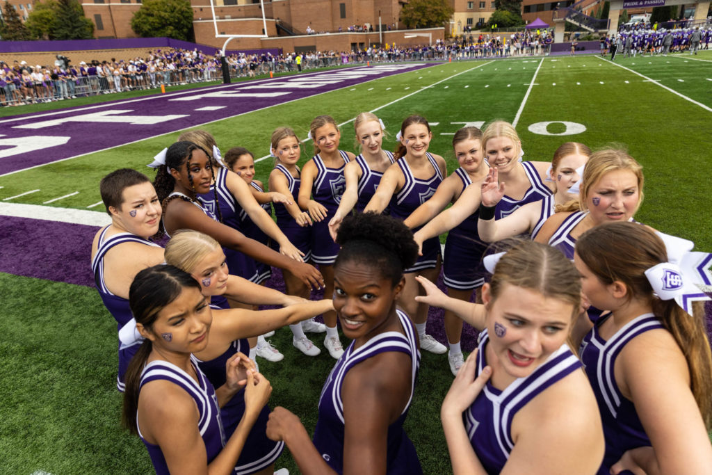 The Cheerleading team huddles during the Homecoming football game. Mark Brown/University of St. Thomas