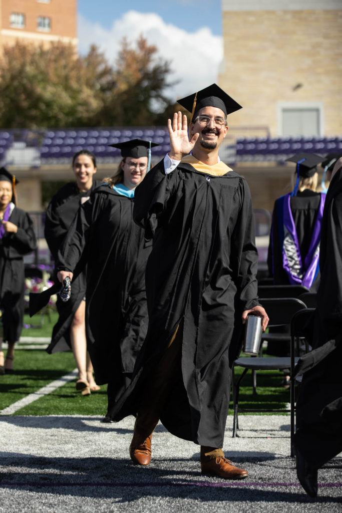 Students wave to family and friends during a commencement.