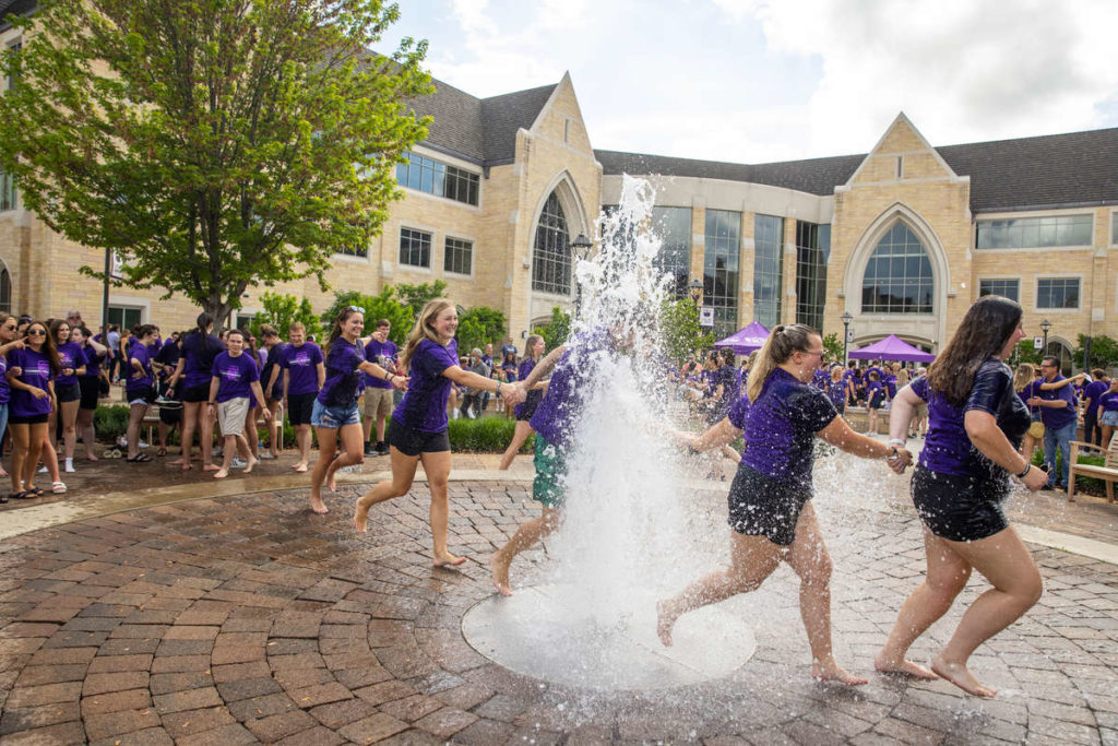 Students run through the water fountain on Monahan Plaza after the annual March Out of the Arches event. Mark Brown/University of St. Thomas