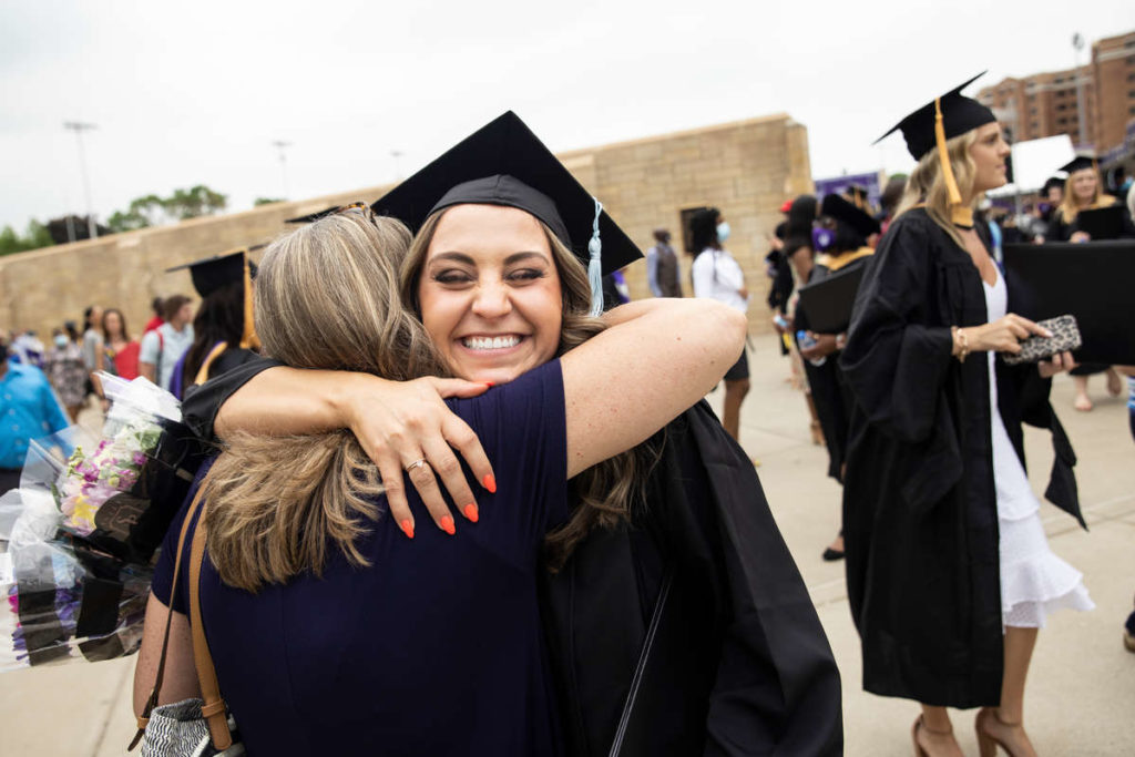 A student smiles while receiving a hug after spring commencement. Mark Brown/University of St. Thomas