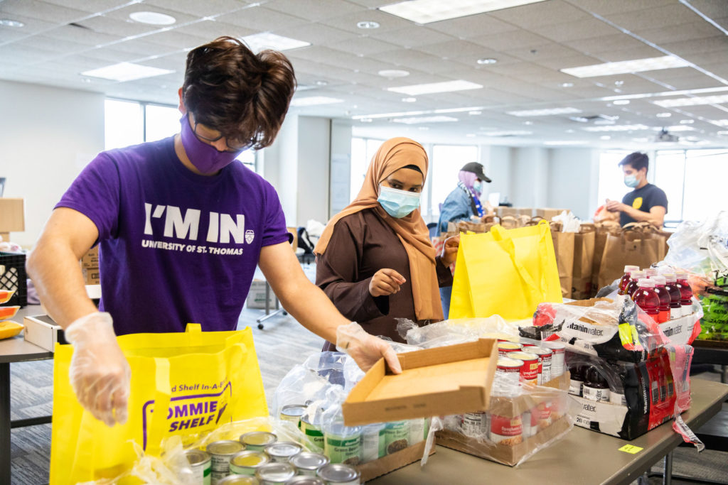 Students Roman Adhikari and Ayan Ahmed work to organize and fill bags of food items in Opus Hall where Tommie Shelf expanded it’s efforts. Liam James Doyle/University of St. Thomas