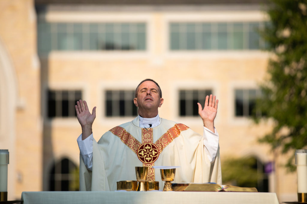 Father Chris Collins prays during the Mass On The Grass service. Liam James Doyle/University of St. Thomas