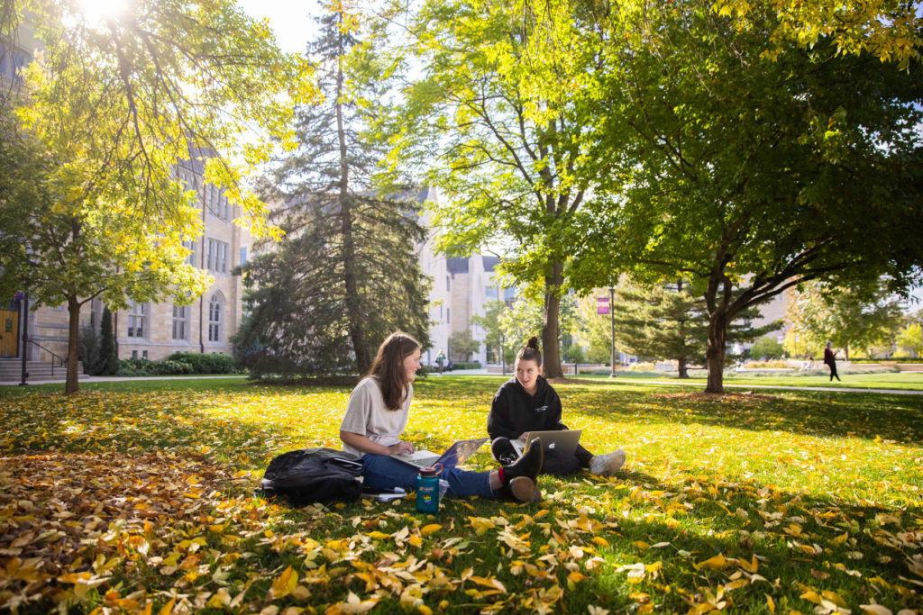 Juniors Ingrid Lindgren, left, and Kate Andrews hang out and do schoolwork together on the lawn of the lower quad. Liam James Doyle/University of St. Thomas