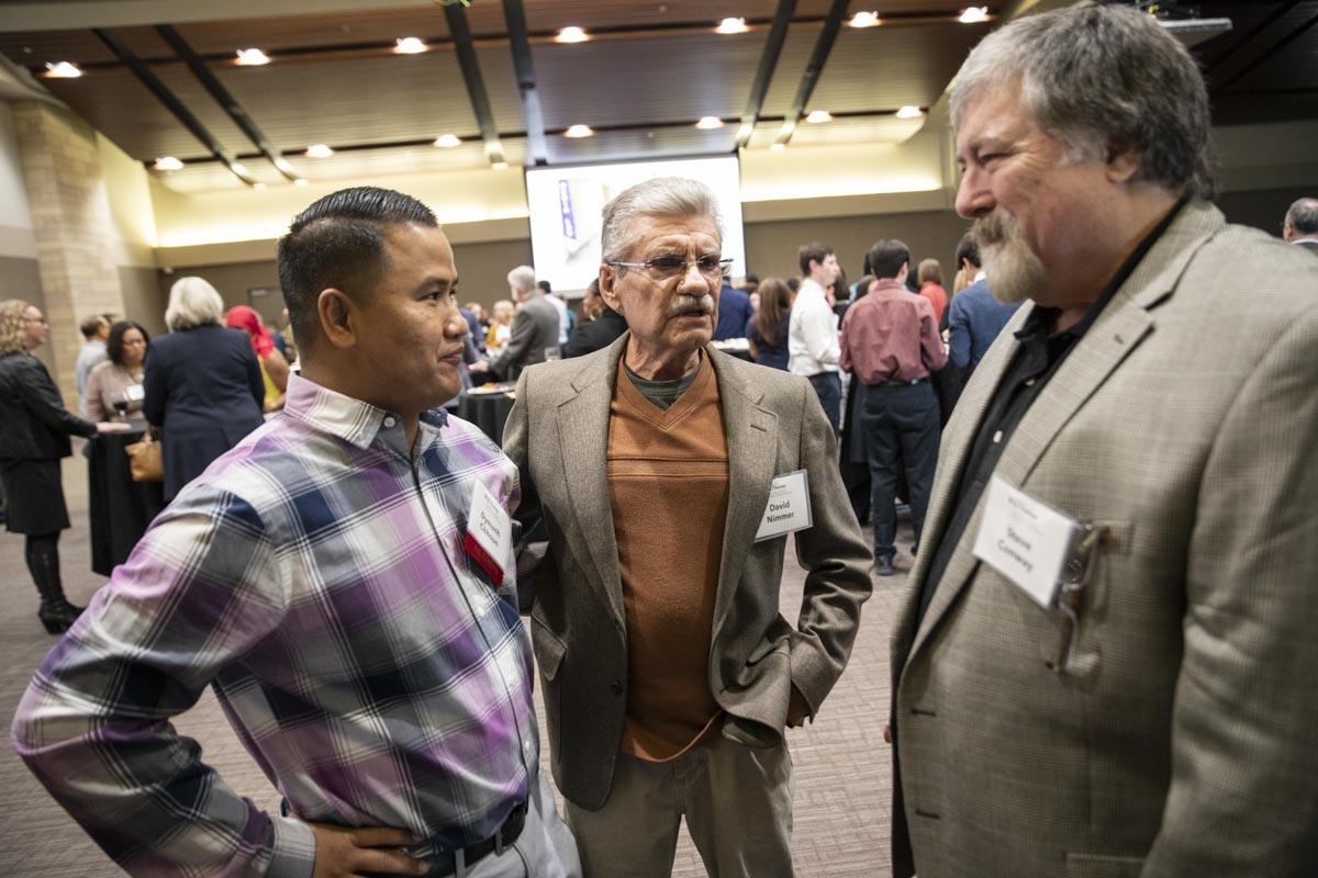 Dymanh Chhoun, program manager at ThreeSixty Journalism, talks with David Nimmer, middle and guest at the ThreeSixty Journalism Homecoming 20th Anniversary Celebration in Woulfe Alumni Hall in St. Paul on April 9, 2022.