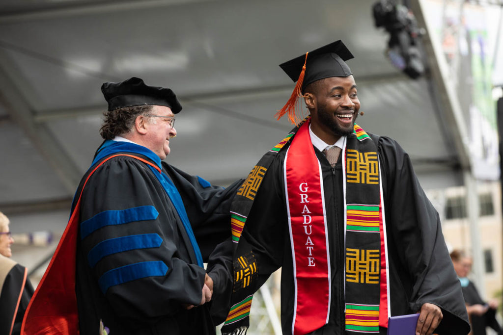 Kevyn Perkins walks across the stage during the 2022 Undergraduate Commencement Ceremony for the Morrison Family College of Health, the School of Education and the School of Engineering on May 21, 2022, in St. Paul.