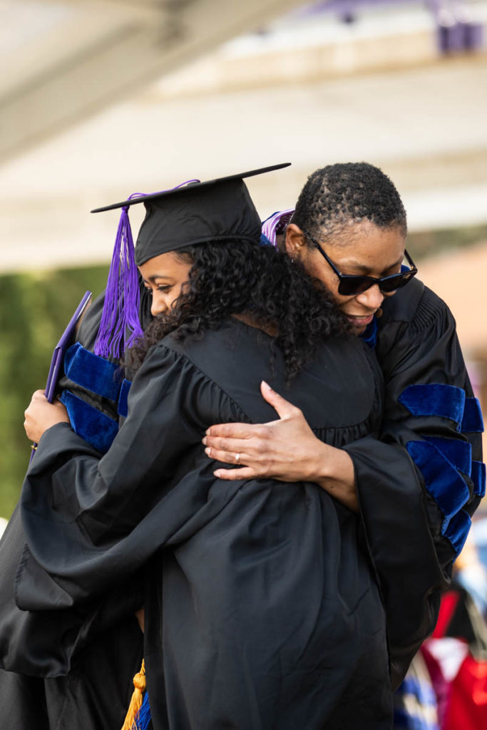 A student gets a hug from DFC Dean Buffy Smith during the 2022 Undergraduate Commencement Ceremony for the Dougherty Family College on May 22, 2022, in St. Paul.