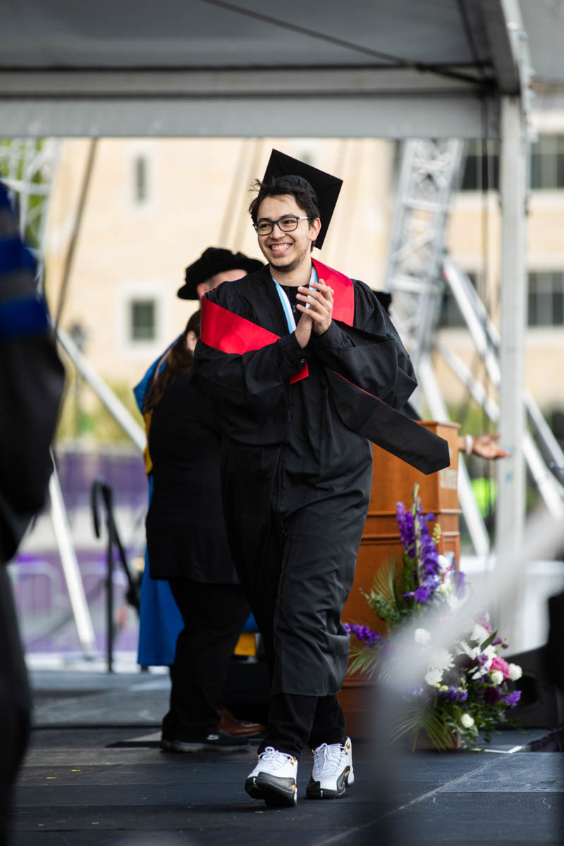 A student walks across the stage during the 2022 Undergraduate Commencement Ceremony for the Dougherty Family College on May 22, 2022, in St. Paul.