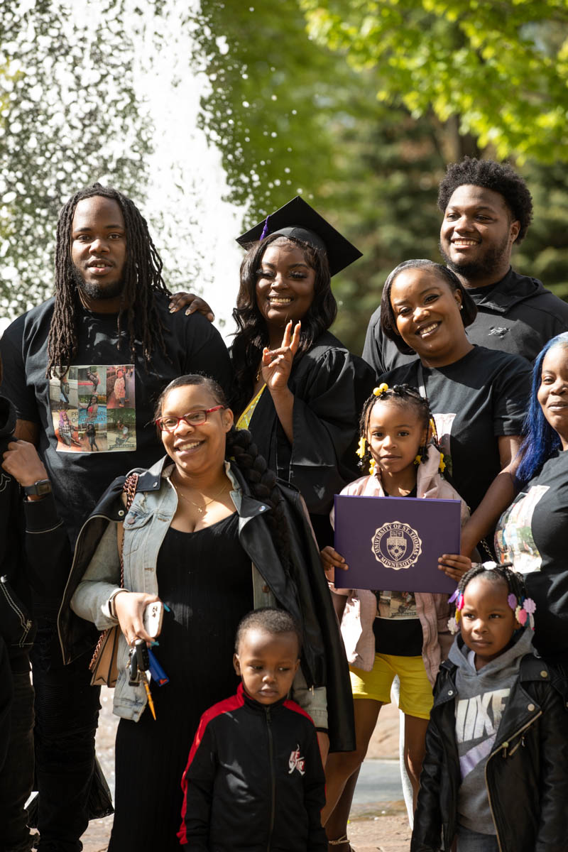 A graduate poses for a family photo after the 2022 Undergraduate Commencement Ceremony for the Dougherty Family College on May 22, 2022, in St. Paul.