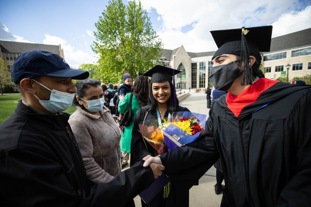 DFC faculty member Amir Mohamed talks with a graduate and her family after the 2022 Undergraduate Commencement Ceremony for the Dougherty Family College on May 22, 2022, in St. Paul.