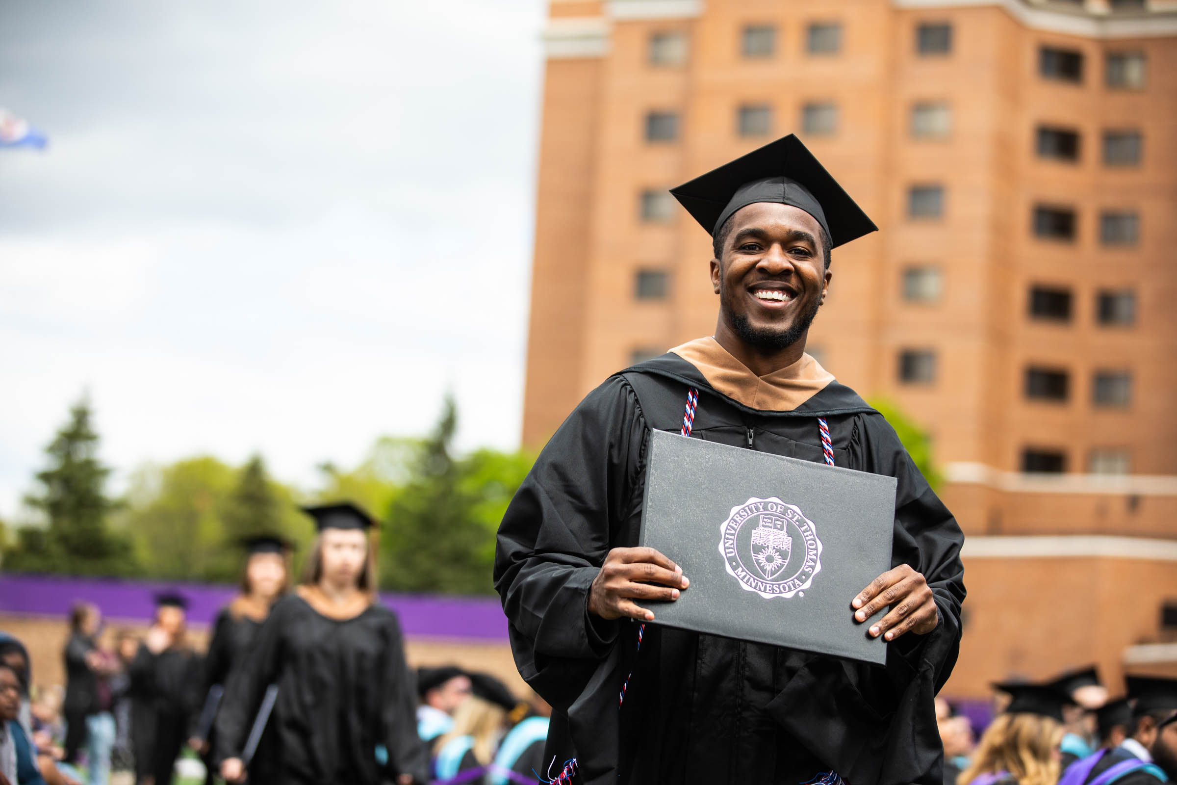 Graduate Gary Cooper shows off his diploma cover during the 2022 Graduate Commencement ceremony for the Opus College of Business, the School of Education and the School of Divinity in St. Paul on May 22, 2022.