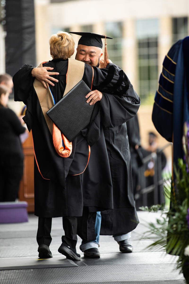 Marketing, Insights and Communications staffer Ed Kim hugs President Julie Sullivan during the 2022 Graduate Commencement ceremony for the Opus College of Business, the School of Education and the School of Divinity in St. Paul on May 22, 2022.