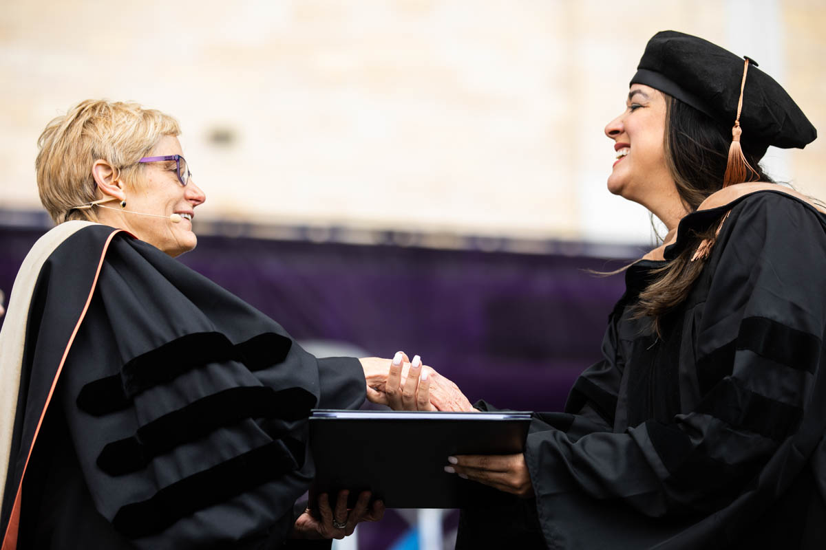President Julie Sullivan shakes hands with a graduate during the 2022 Graduate Commencement ceremony for the Opus College of Business, the School of Education and the School of Divinity in St. Paul on May 22, 2022.