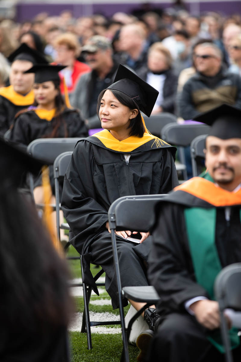 A student smiles during the 2022 Graduate Commencement ceremony for the College of Arts and Sciences, the Morrison Family College of Health and the School of Engineering in St. Paul on May 22, 2022.