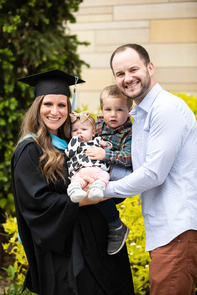 A family poses for a photo after the 2022 Graduate Commencement ceremony for the College of Arts and Sciences, the Morrison Family College of Health and the School of Engineering in St. Paul on May 22, 2022.