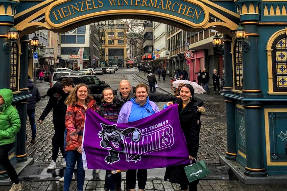 University of St. Thomas students hold a school flag while on a study abroad trip to Germany