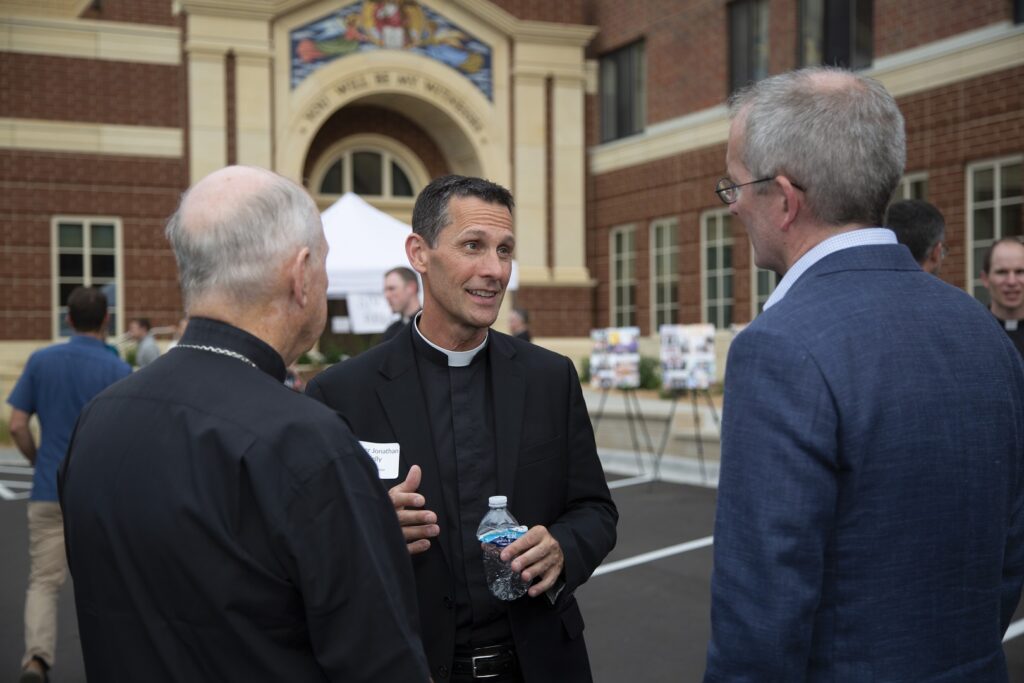 Father Kelly speaks with President Rob Vischer.