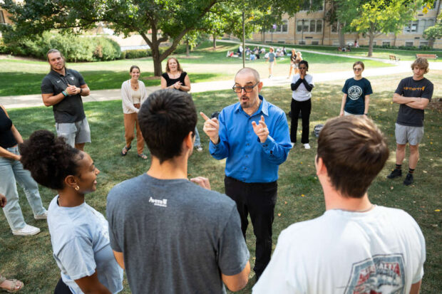 Communications Professor Bernie Armada leads students during and improvisation exercise during an outdoor class session on the quad.