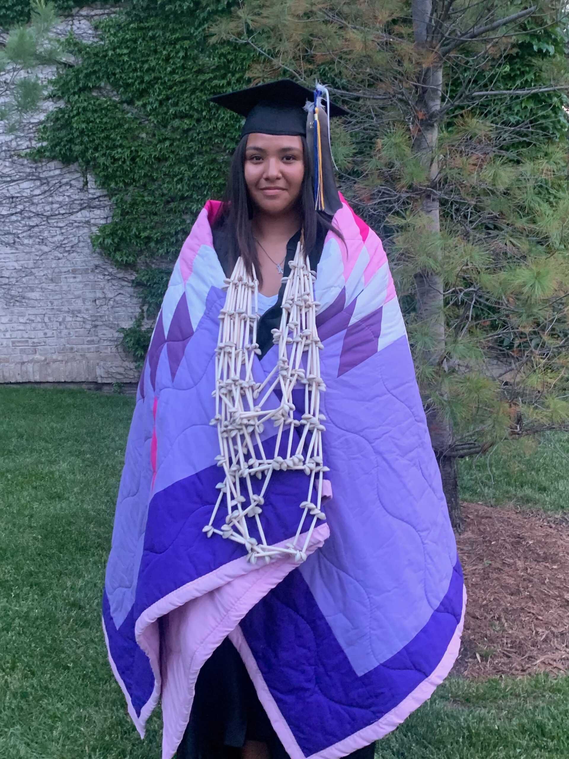 Keya Luta Win Hunt poses in a star quilt at her high school graduation. The quilt was created by a member of the Lower Sioux community.