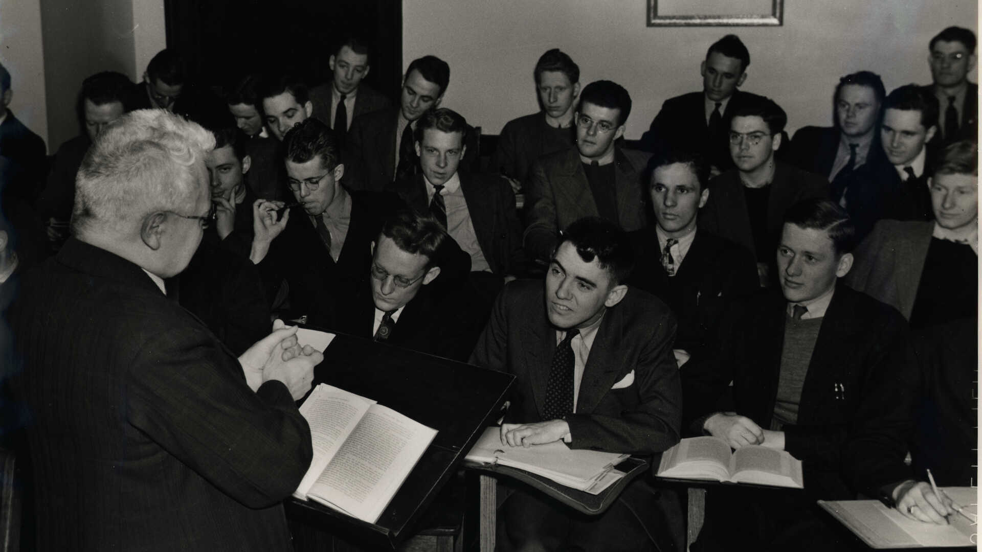 Professor Theodor Brauer stands at the podium instructing an economics class at the College of St. Thomas, 1939.