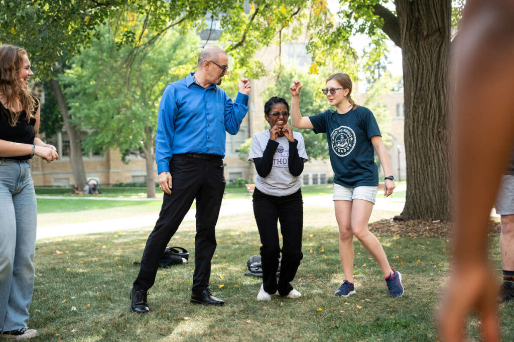 Communications Professor Bernie Armada leads students during and improvisation exercise during an outdoor class session on the quad on September 21 in St. Paul.