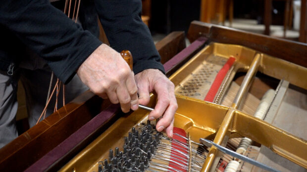 A person works to deconstruct an old piano at Keys 4/4 Kids in New Brighton, MN.