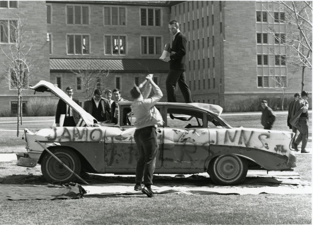 Student hammering a car.