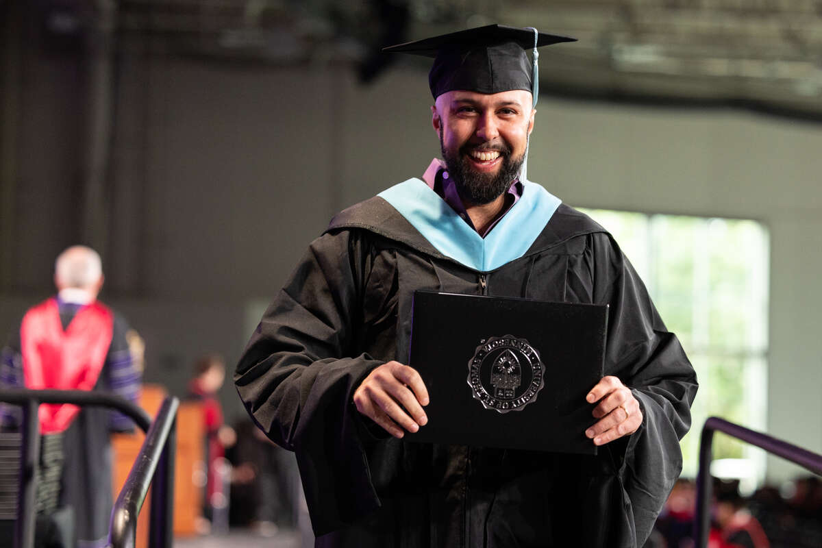 A student smiles during the Graduate Commencement Ceremony for the College of Arts and Sciences, The School of Divinity, the School of Engineering and the School of Education on May 26, 2024 in St. Paul.