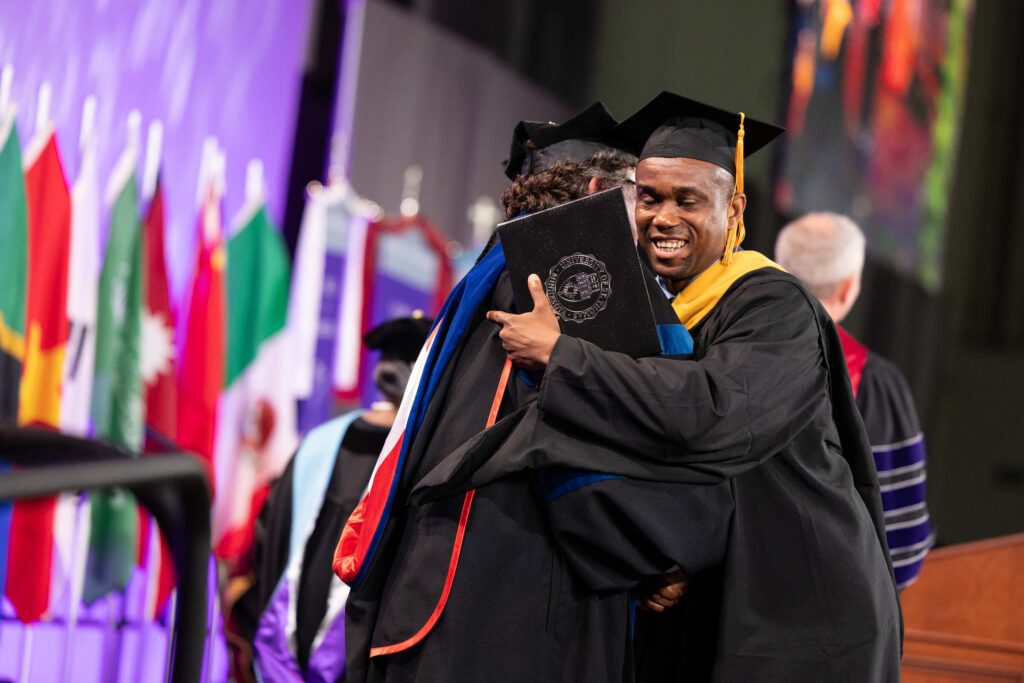 A student shake hugs Engineering Dean Don Weinkauf during the Graduate Commencement Ceremony for the College of Arts and Sciences, The School of Divinity, the School of Engineering and the School of Education on May 26, 2024 in St. Paul.